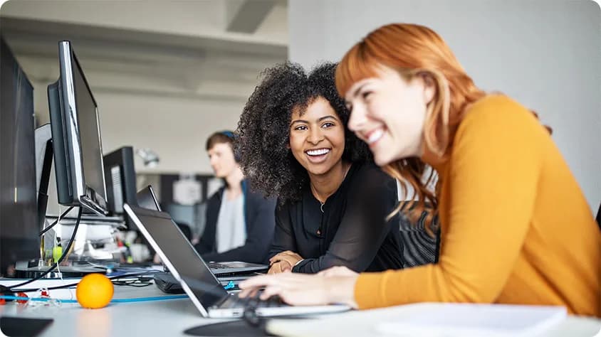 Two women colleagues in front of a computer in an office